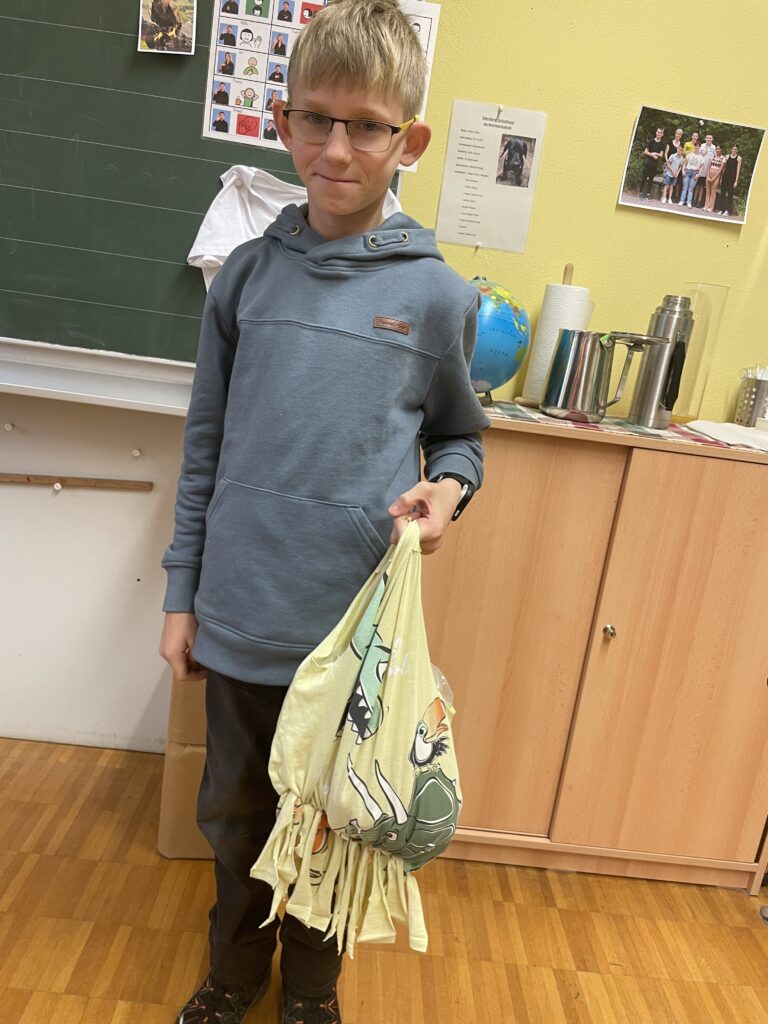 Schüler zeigt eine Tasche, die er aus einem alten T-Shirt gestaltet hat